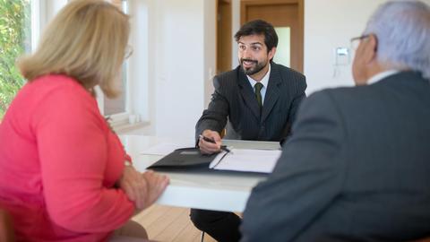 A real estate agent discussing a deal with senior clients in an office setting.