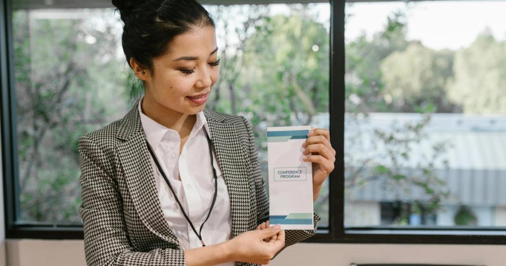 Young professional woman holding a conference program brochure indoors.