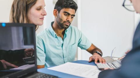 A young couple in discussion with a real estate agent in a modern office setting.