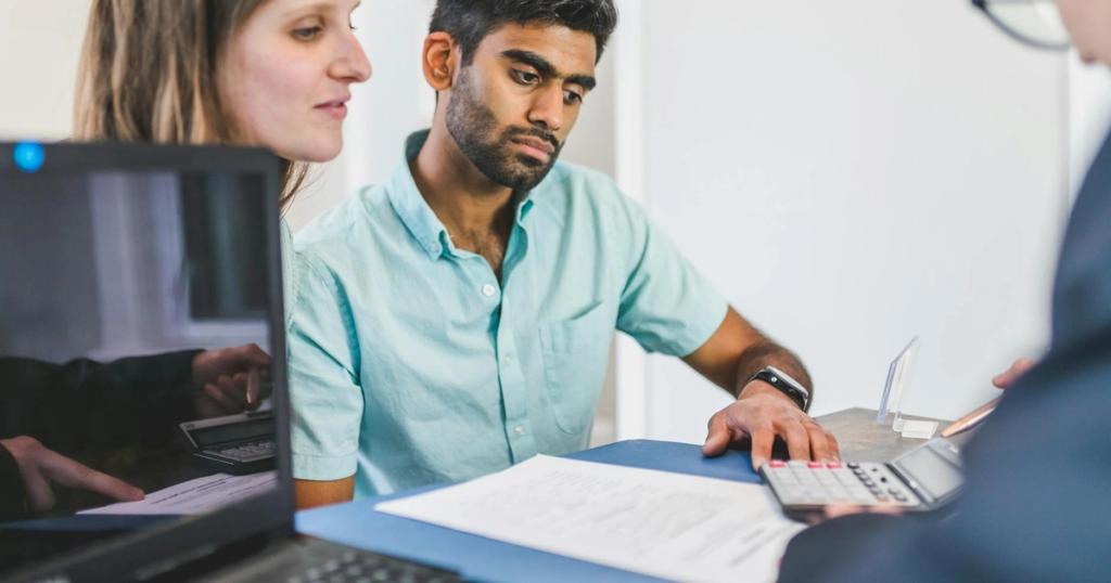 A young couple in discussion with a real estate agent in a modern office setting.