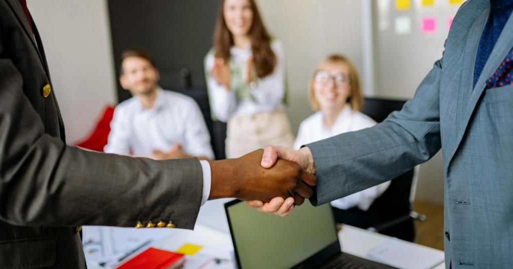 Close-up of a handshake between colleagues in a professional office setting, emphasizing teamwork and agreement.
