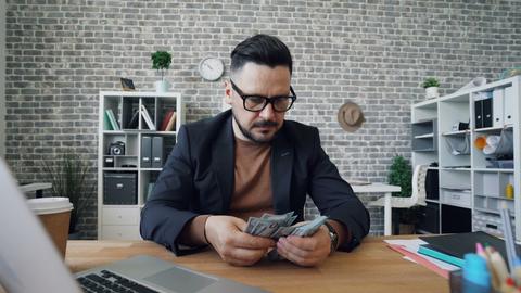 a man sitting at a table with a laptop and money