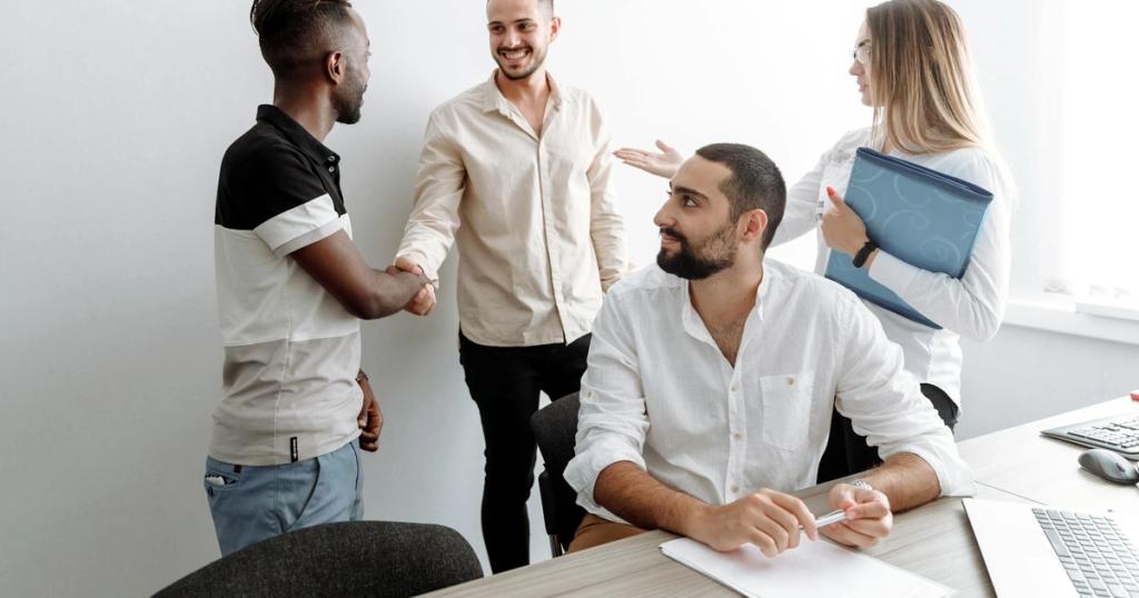 A team of diverse professionals shaking hands and smiling in an office setting, symbolizing cooperation.