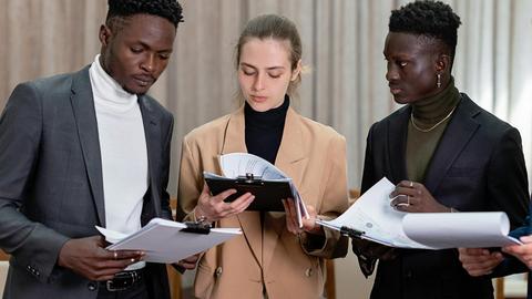 A multi-ethnic group of professionals reviewing documents together in a corporate setting.