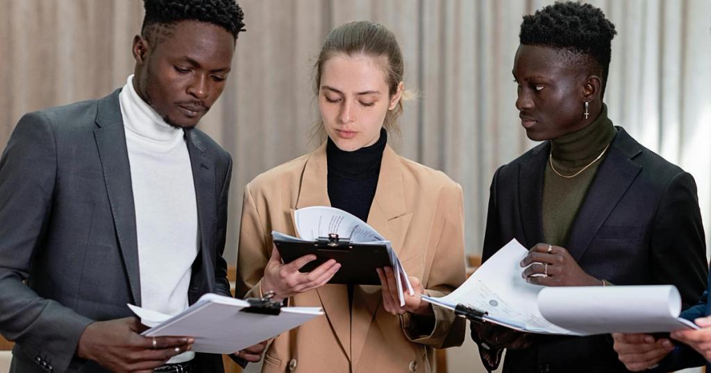 A multi-ethnic group of professionals reviewing documents together in a corporate setting.