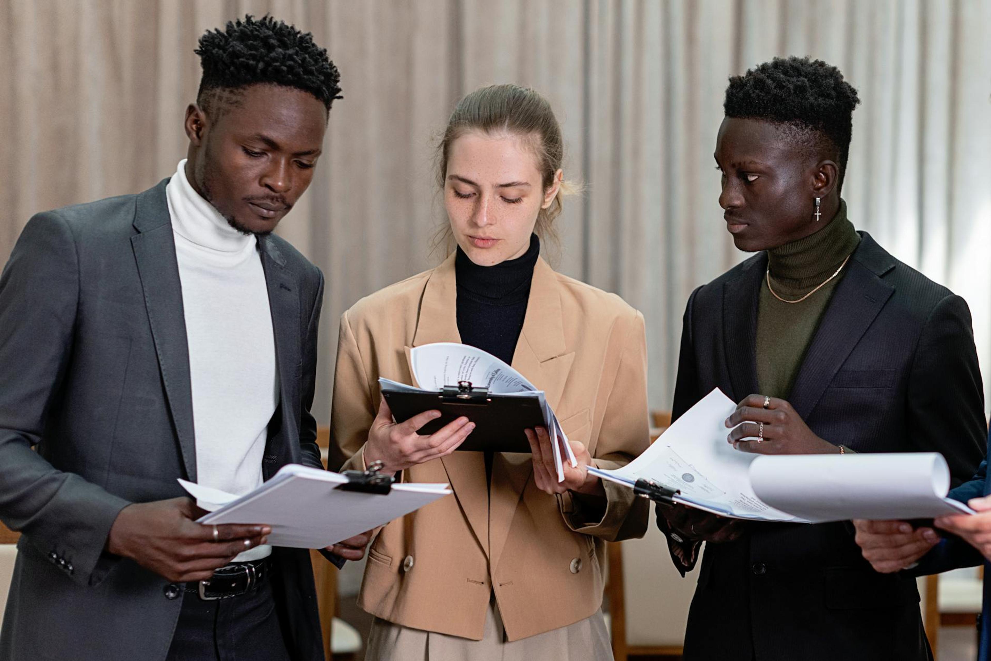 A multi-ethnic group of professionals reviewing documents together in a corporate setting.