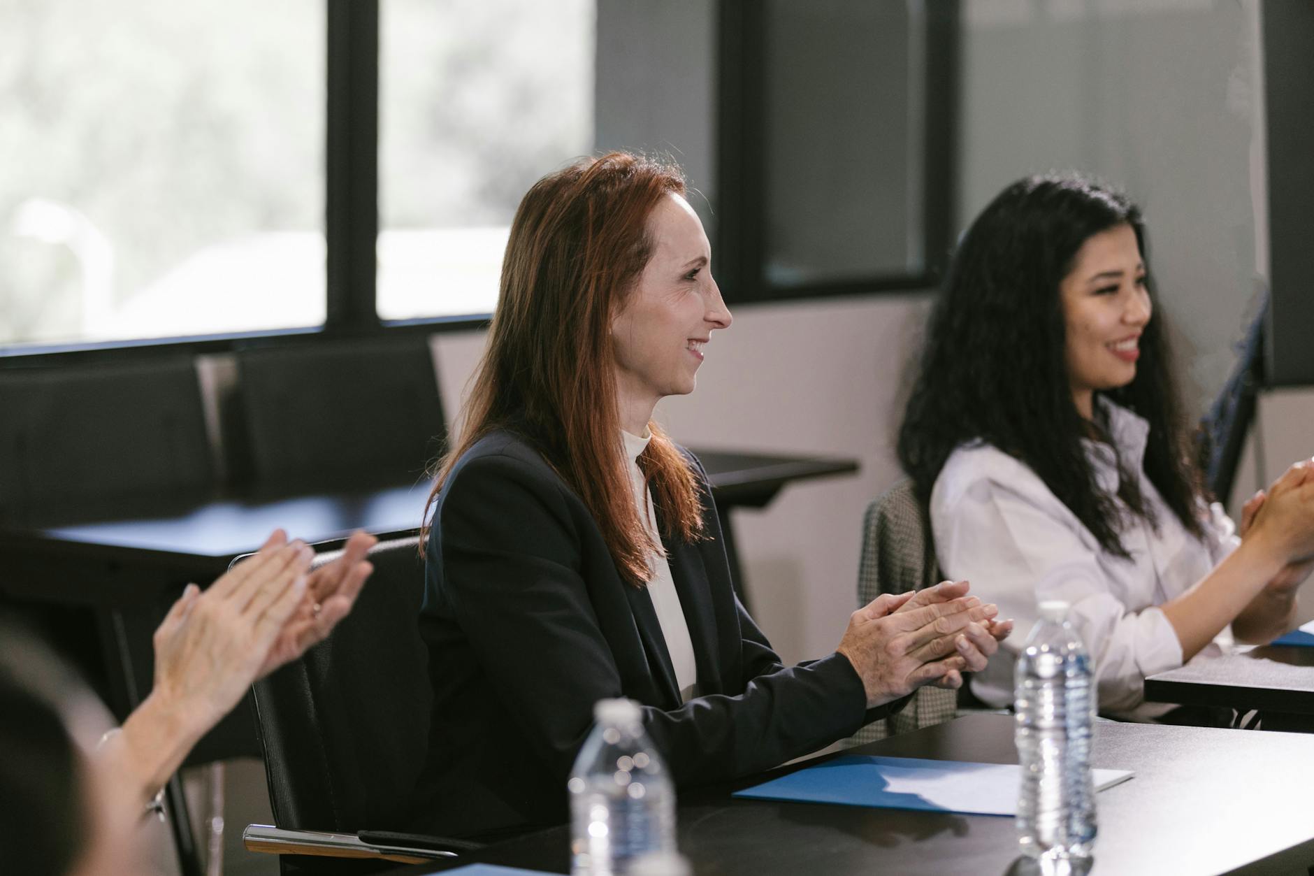 Business professionals engaged in a positive meeting, clapping in appreciation.