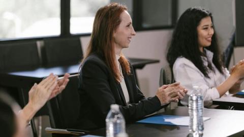 Business professionals engaged in a positive meeting, clapping in appreciation.