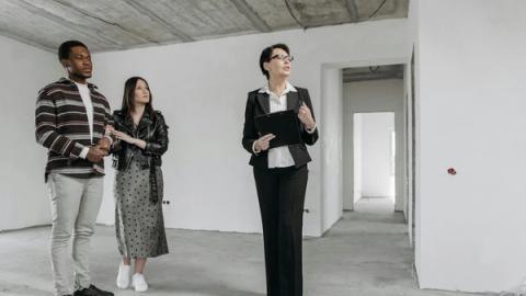 A real estate agent shows an unfinished apartment to prospective buyers.