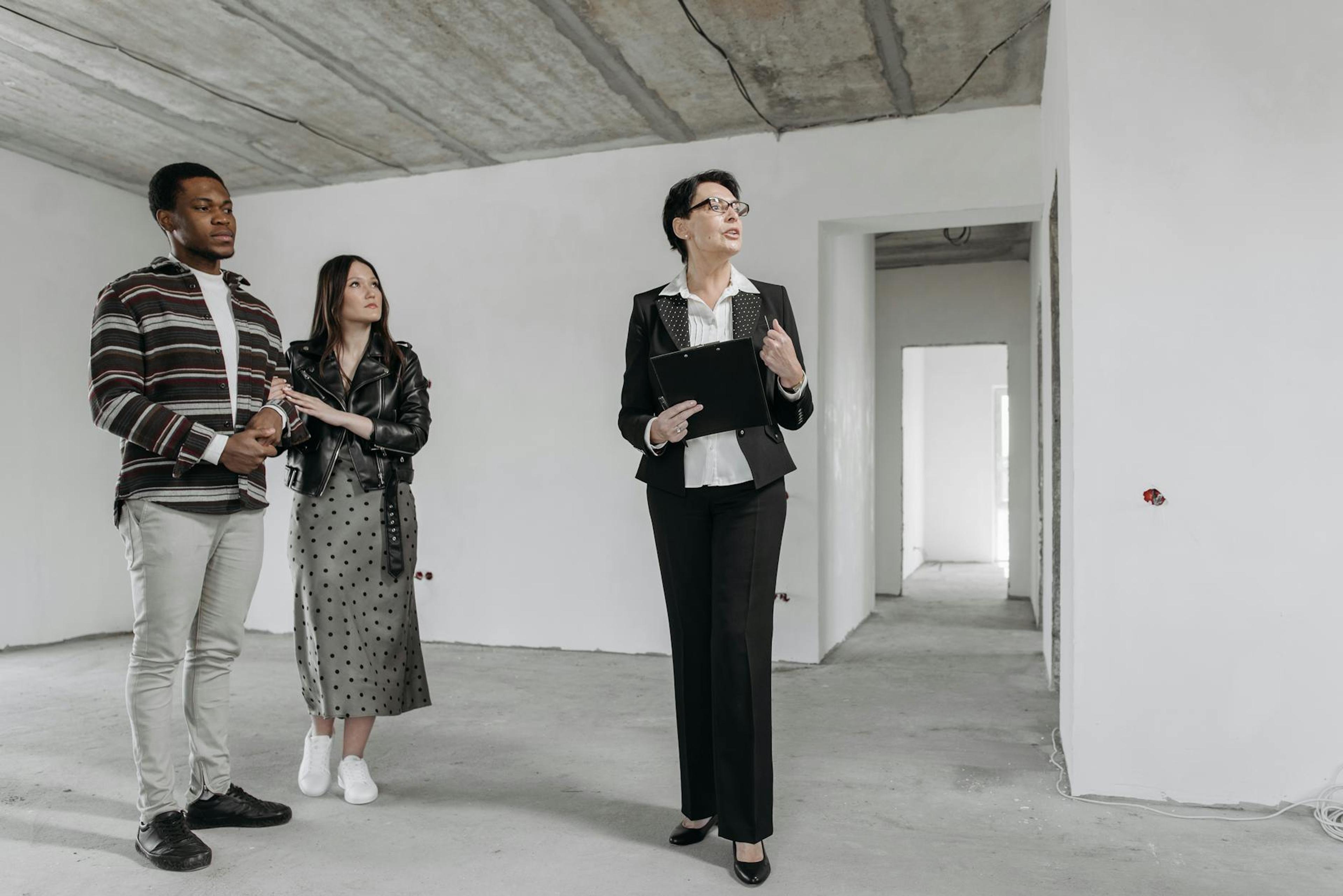 A real estate agent shows an unfinished apartment to prospective buyers.