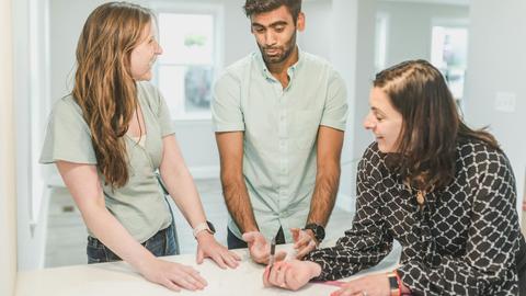 Three adults having a discussion about real estate in a modern home setting.