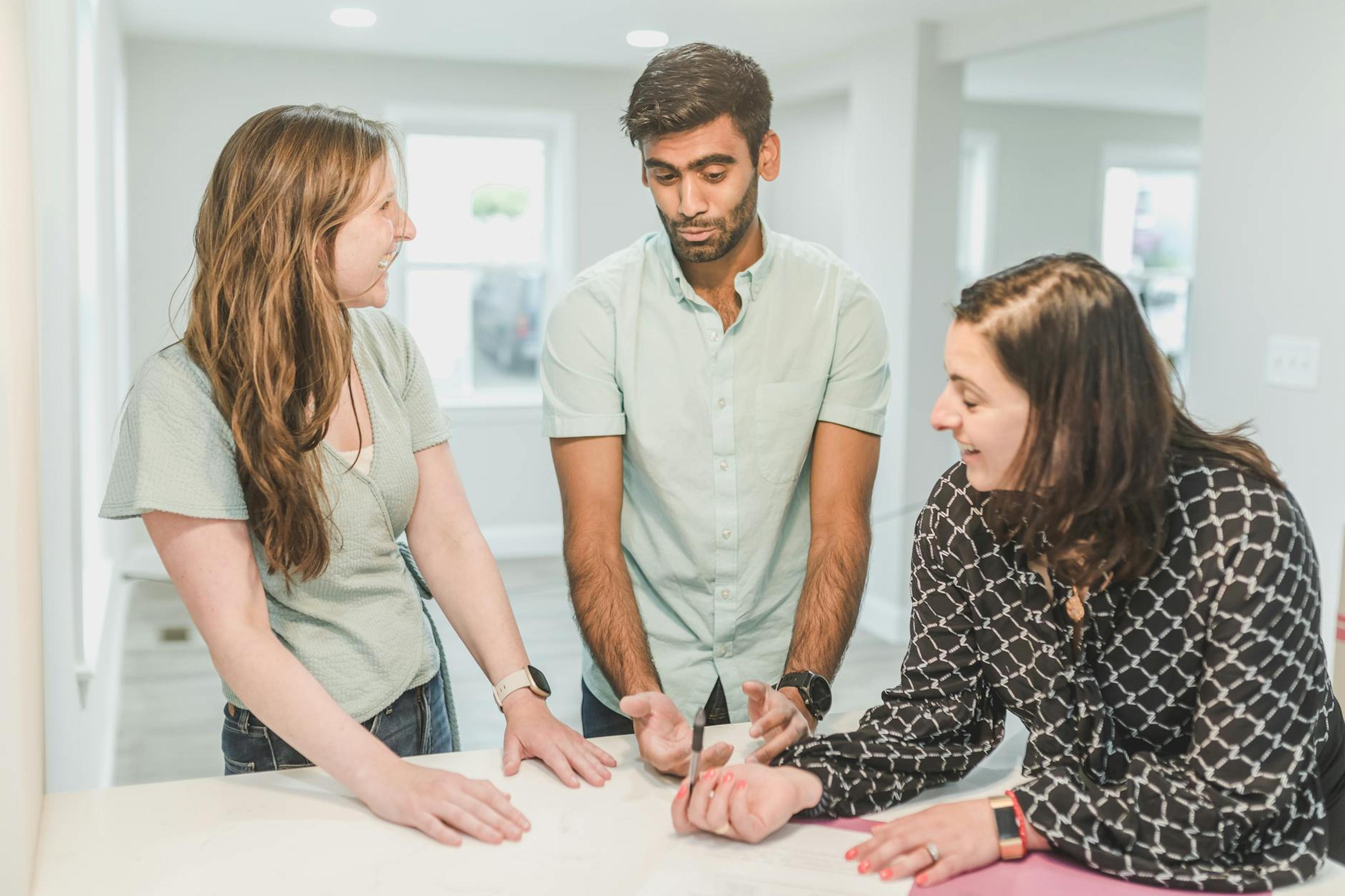 Three adults having a discussion about real estate in a modern home setting.