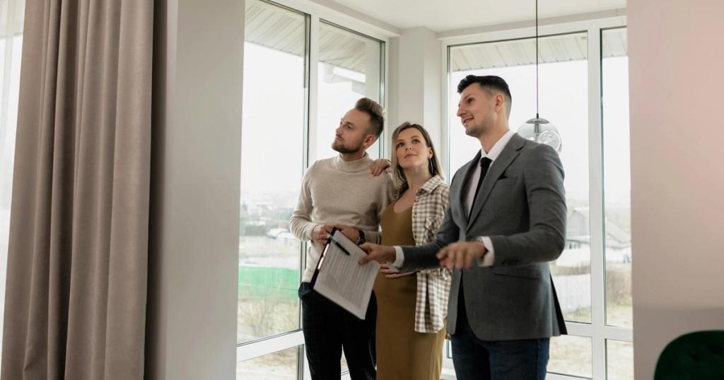 A real estate agent showing a modern home to a young couple during a daytime viewing.