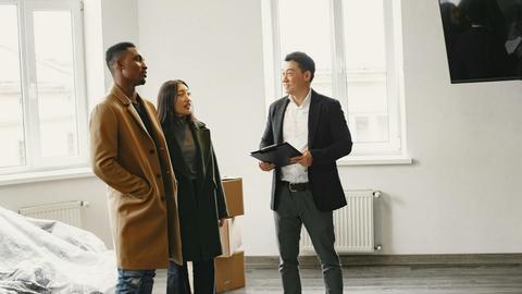 Real estate agent discussing property details with a couple in a modern room.
