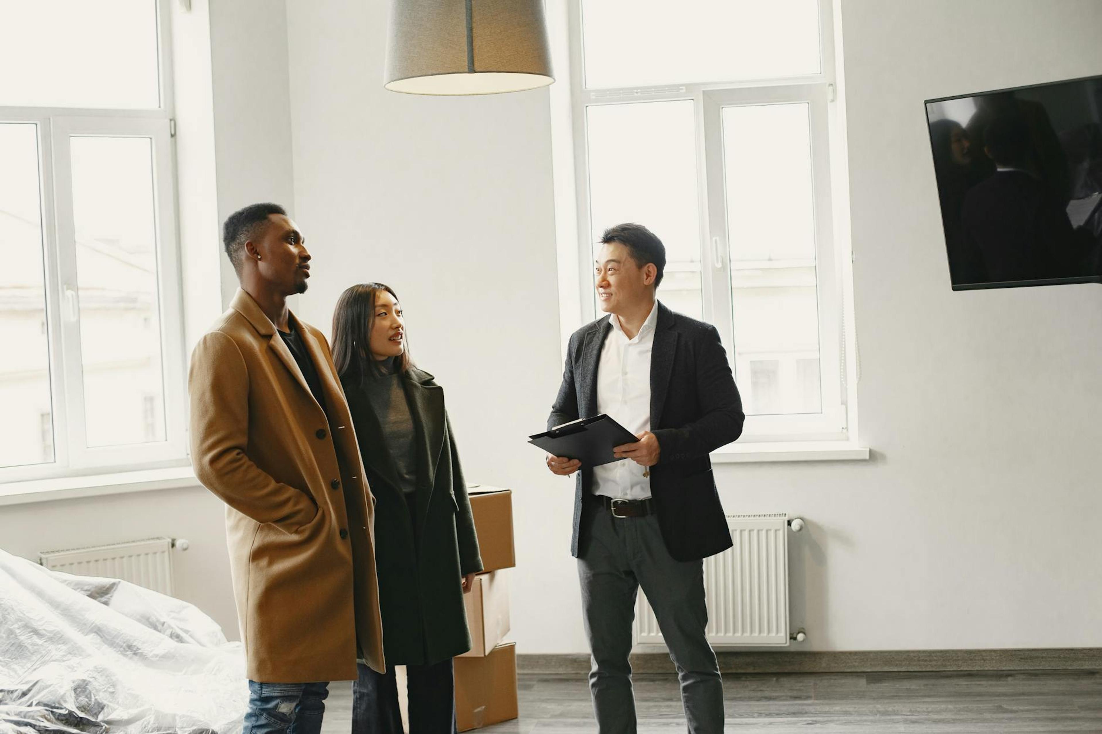 Real estate agent discussing property details with a couple in a modern room.