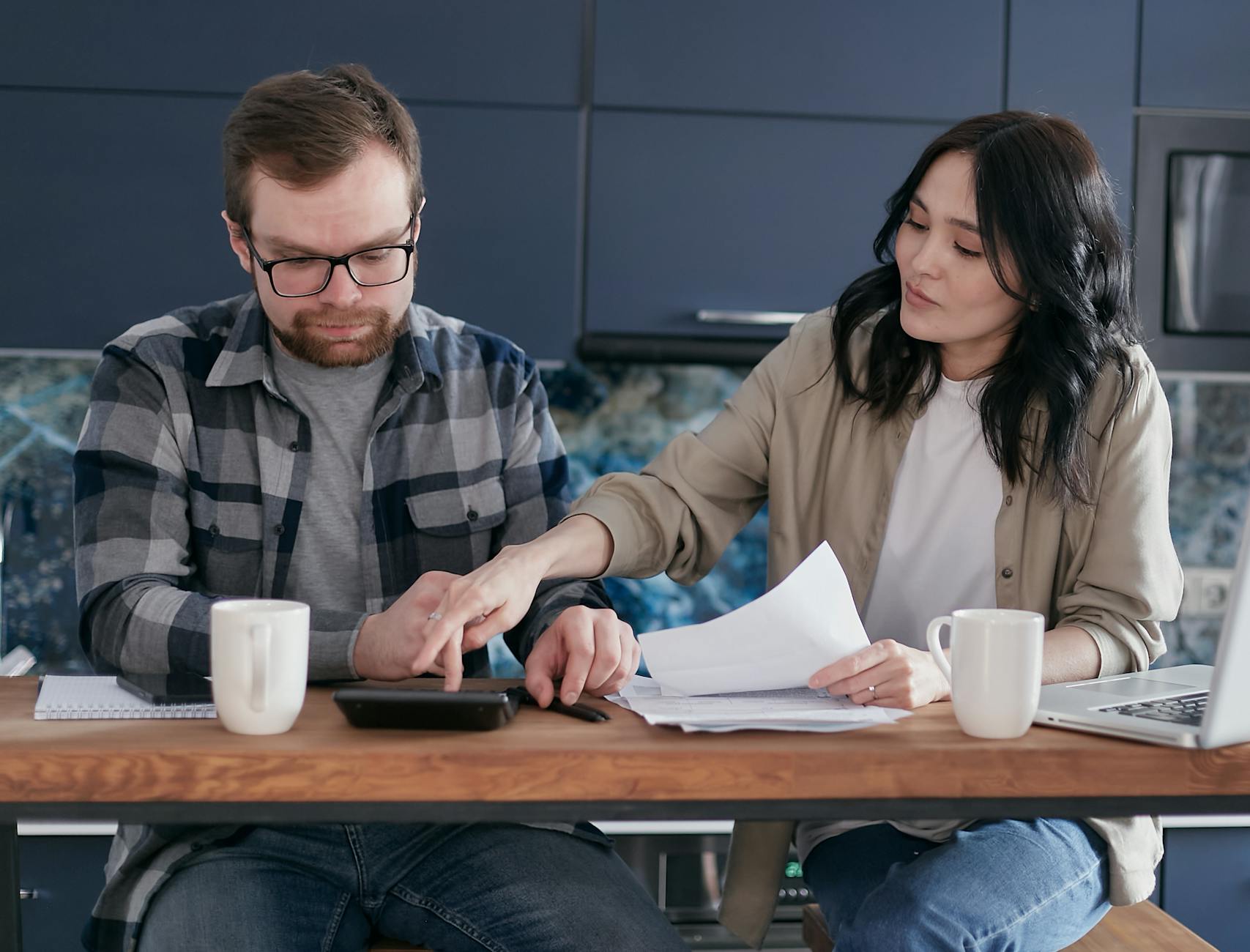 A couple working on their finances together at home, showing teamwork and collaboration.