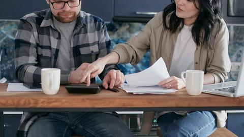 A couple working on their finances together at home, showing teamwork and collaboration.