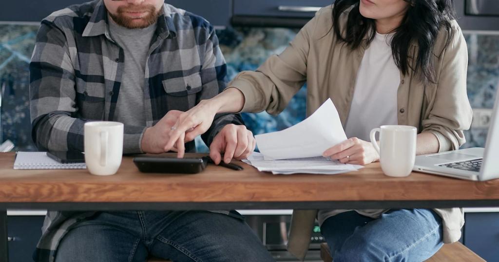 A couple working on their finances together at home, showing teamwork and collaboration.