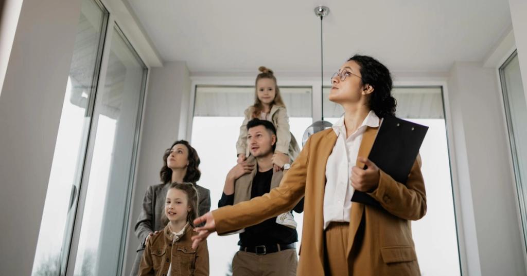 A family with children tours a modern home guided by a real estate agent.