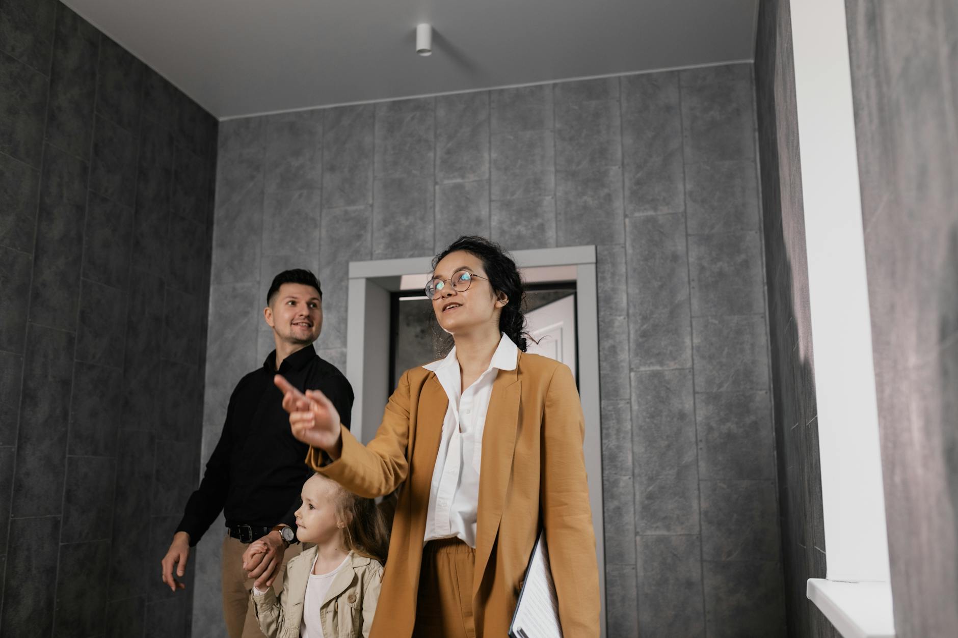 A family explores a modern home interior with a professional realtor guiding them.