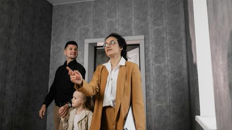 A family explores a modern home interior with a professional realtor guiding them.