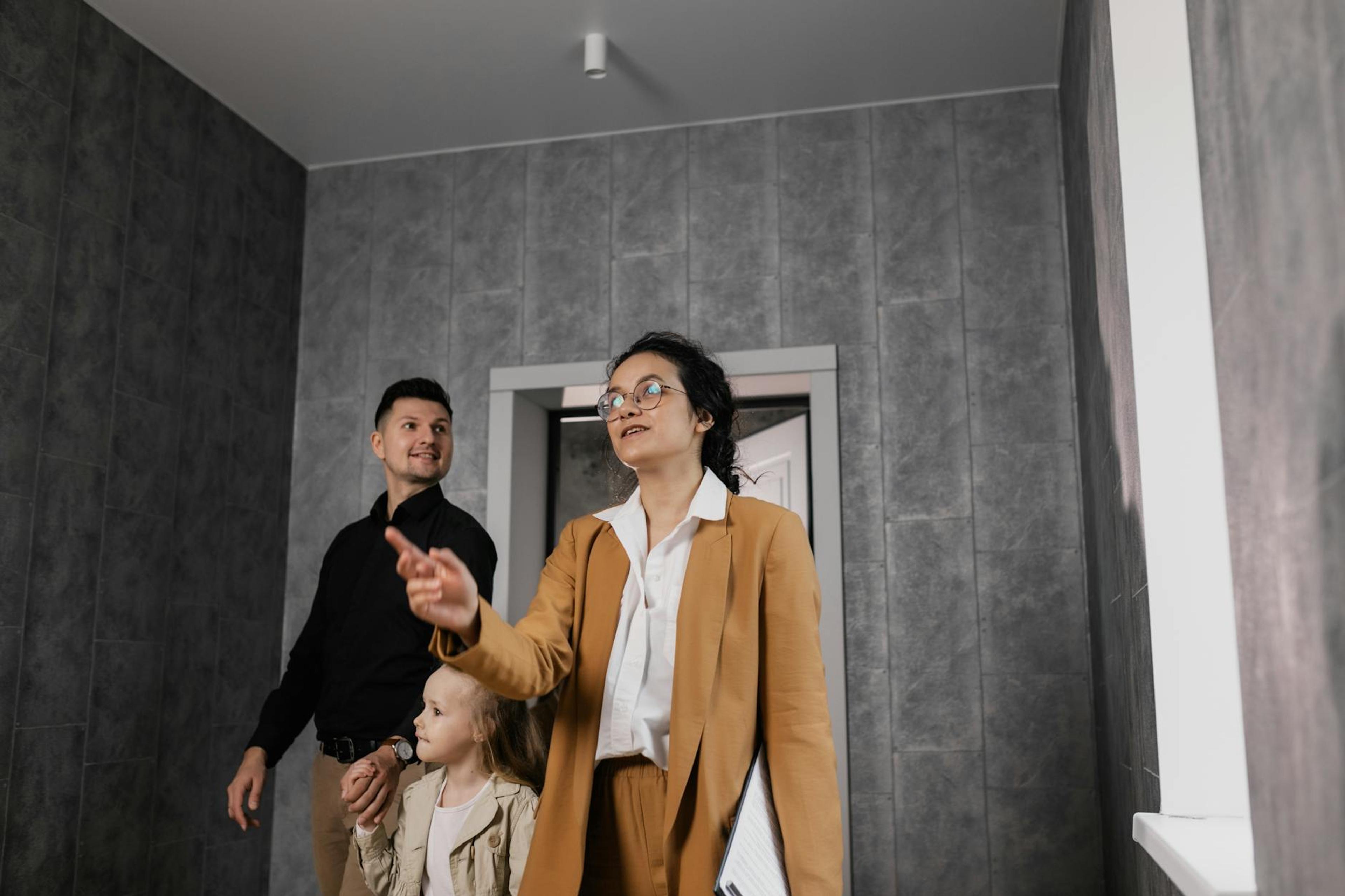 A family explores a modern home interior with a professional realtor guiding them.