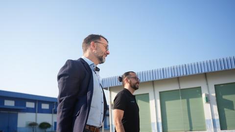 Two men walking outside industrial buildings