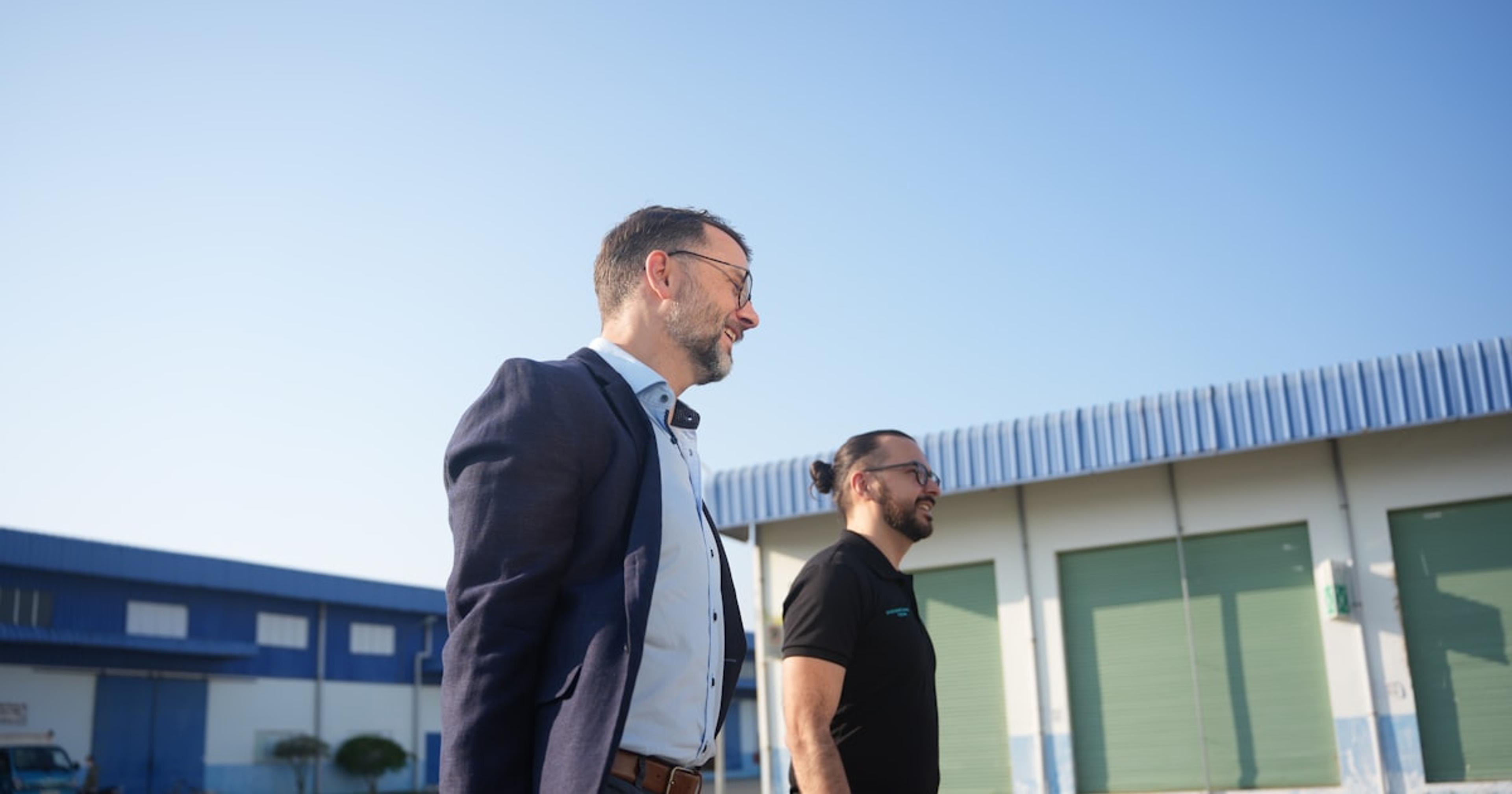 Two men walking outside industrial buildings