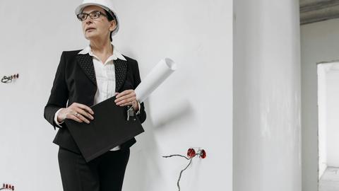 Professional woman in hard hat evaluating building interior. Ideal for construction and real estate themes.