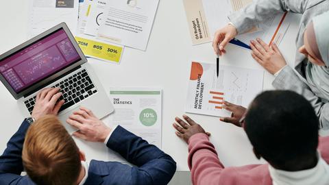 Business meeting with professionals discussing financial reports and graphs at a work desk.
