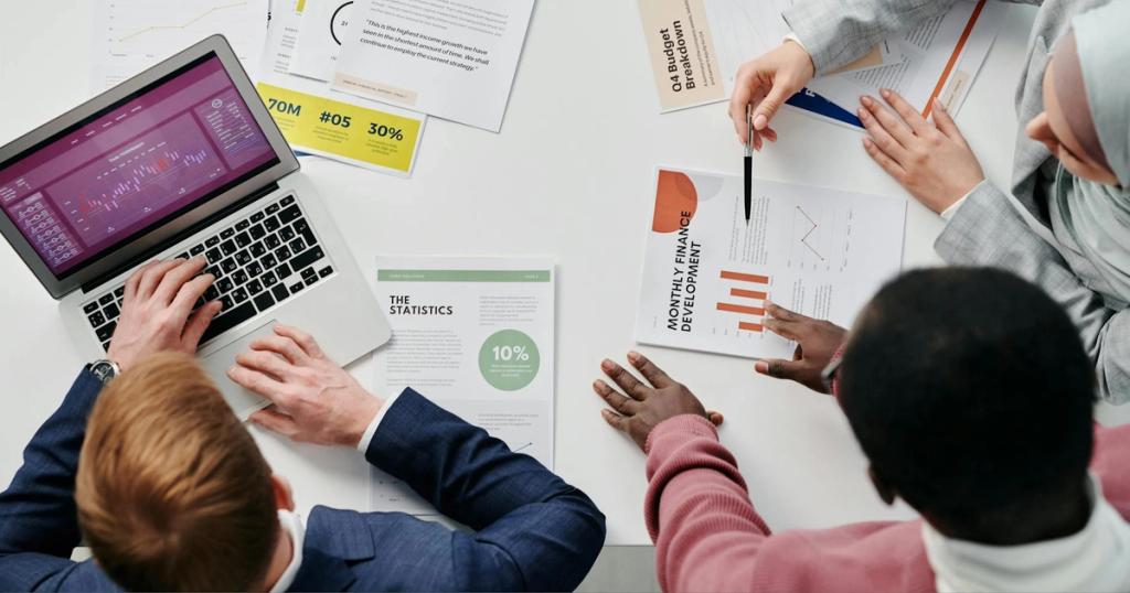 Business meeting with professionals discussing financial reports and graphs at a work desk.