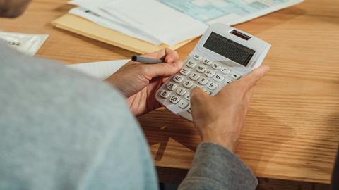 Person using a calculator at a desk with financial documents. Modern business concept.