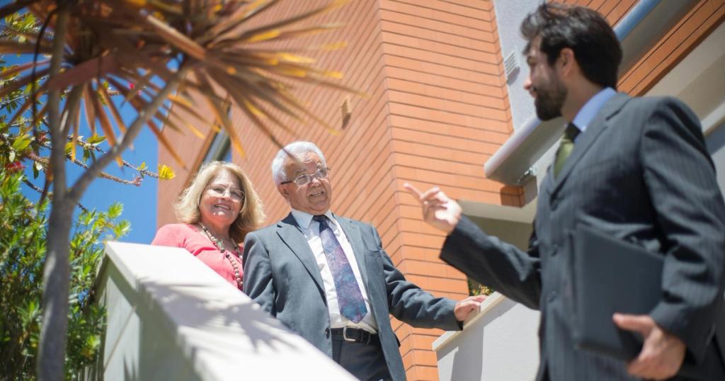 Elderly couple touring a modern home with a real estate agent in sunny Portugal.