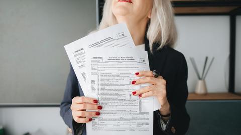 Businesswoman holding tax documents, ready for filing or review, in a professional office setting.