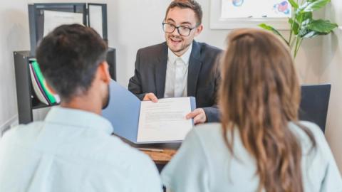A businessman discusses a contract with clients in a modern office setting.