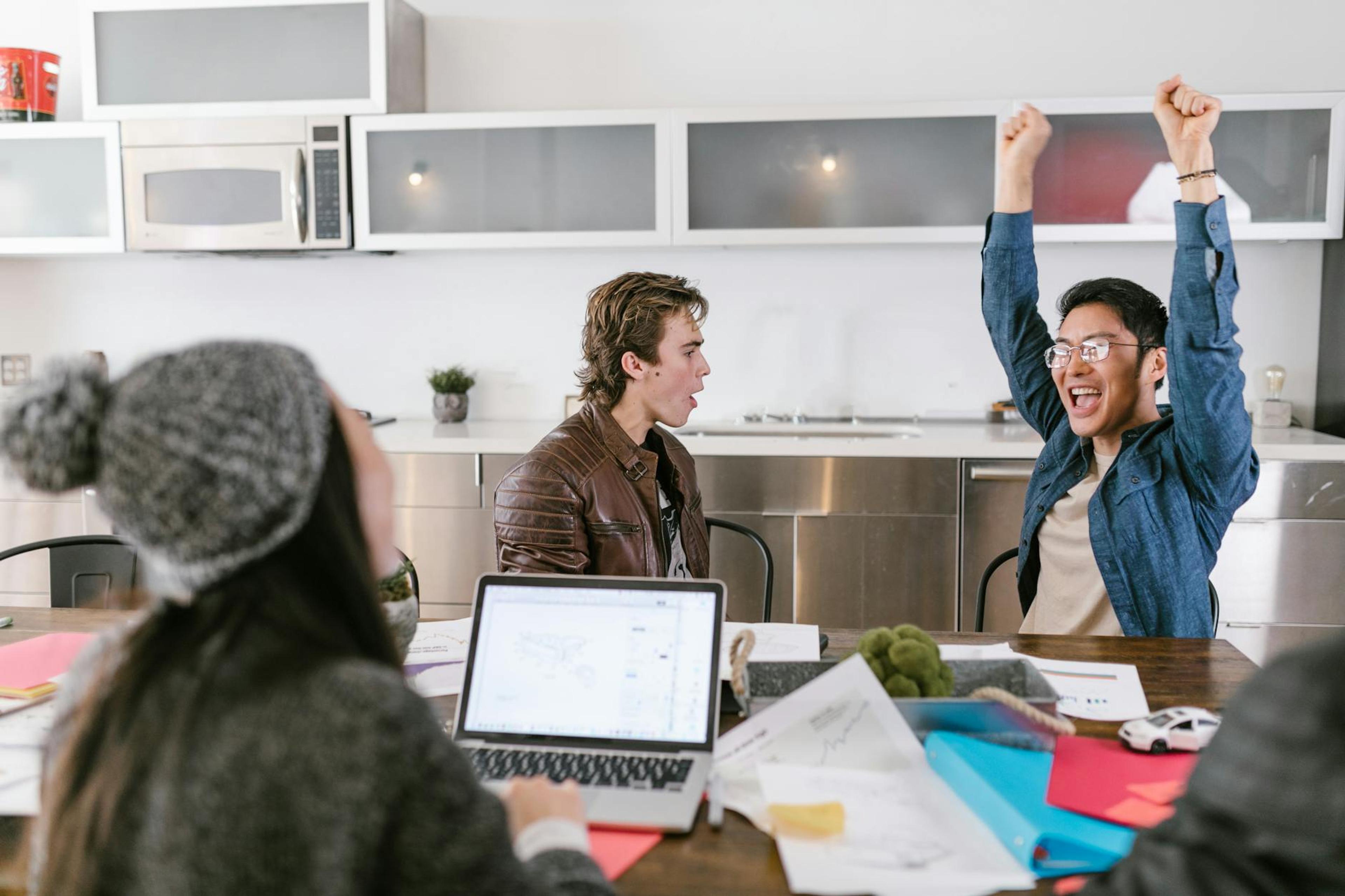 Team of coworkers celebrating after a successful meeting in a modern office.
