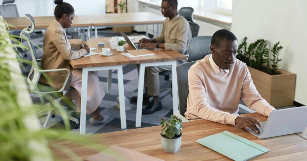 Diverse group working in a modern office setting with laptops and wooden desks.