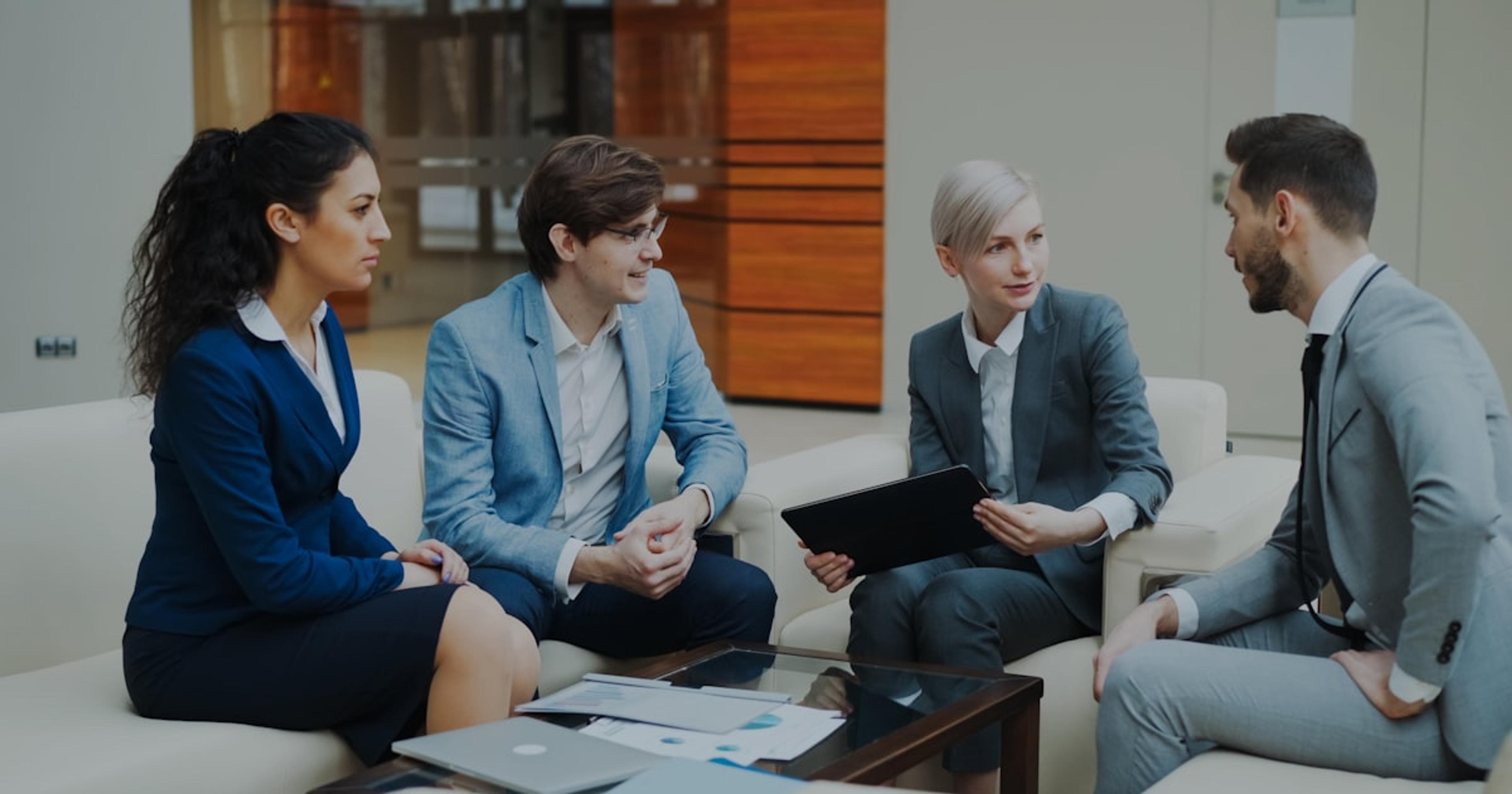 Four business people in a meeting discussing documents.