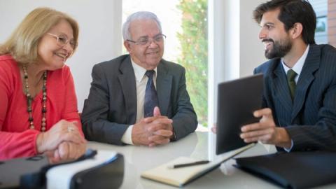 Elderly couple discussing real estate options with an agent in a modern office setting.