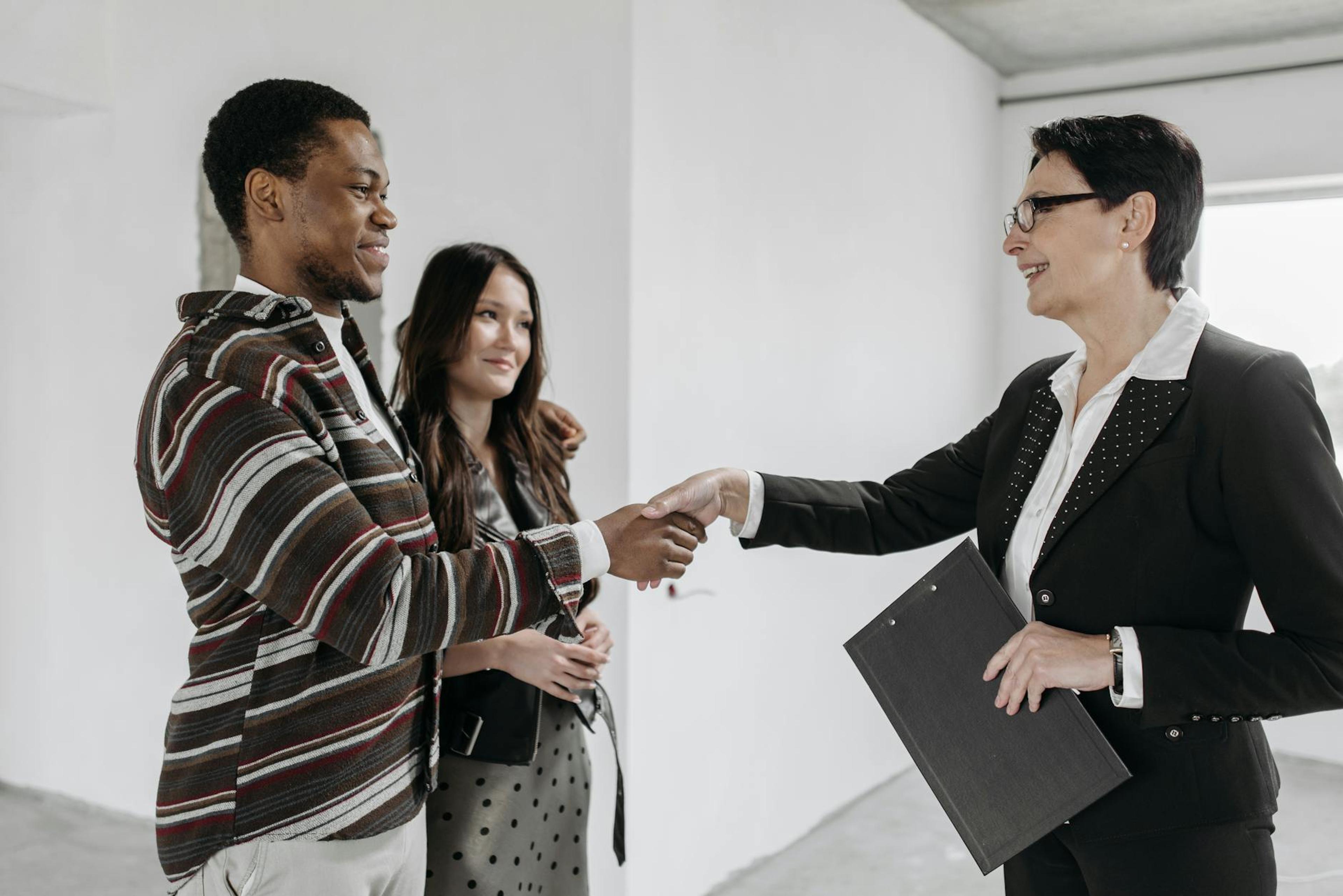 Business professionals shake hands in a modern office, symbolizing a successful deal.