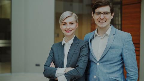 A man and woman in business attire smiling.