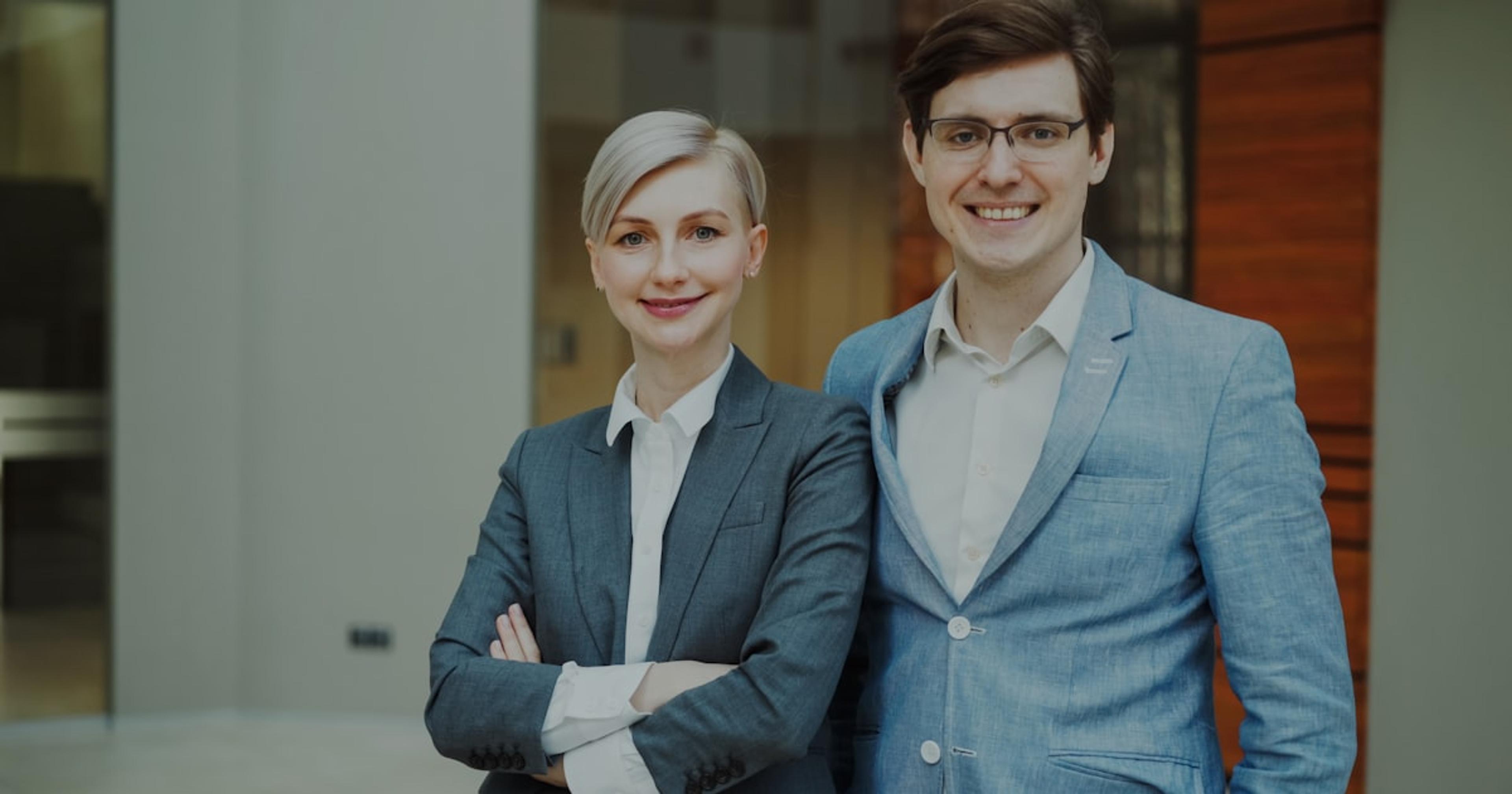 A man and woman in business attire smiling.