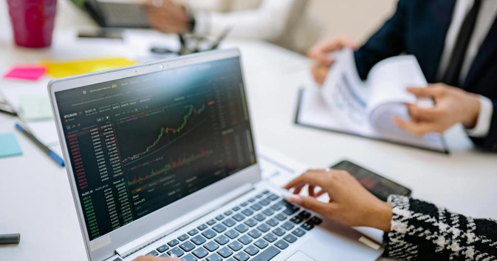 Business team analyzes cryptocurrency market trends using a laptop with graphs and data.