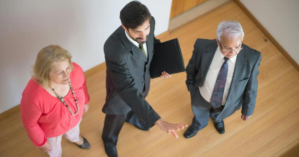 A realtor shows a property to a senior couple in a modern indoor setting.