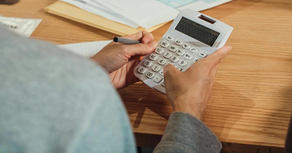 Person using a calculator at a desk with financial documents. Modern business concept.