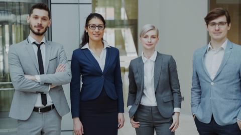 Four business professionals standing together indoors.