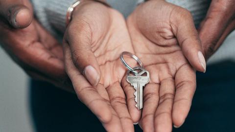 Close-up of hands holding a key, symbolizing homeownership, real estate, and property investment.
