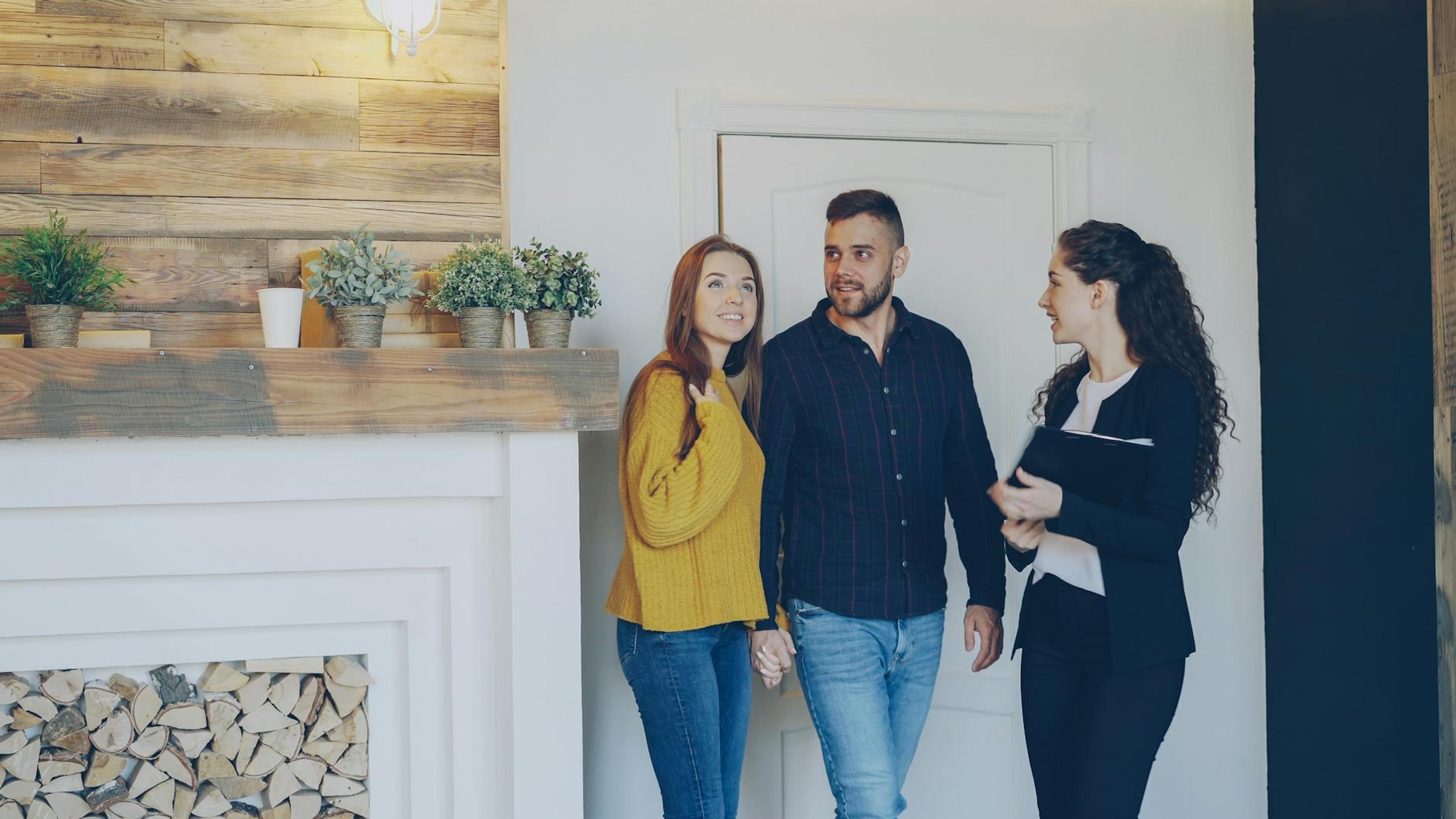Young couple meeting with real estate agent inside cozy home, exploring purchase options.