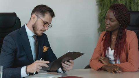 A man and woman engaging in a job interview in a modern office setting.