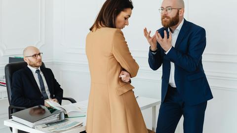A group of business colleagues in a heated discussion at the office, showcasing workplace dynamics.
